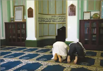  ??  ?? Two men pray at Woking’s Shah Jahan Mosque which, earlier this year, became the first Grade I-listed mosque in Britain