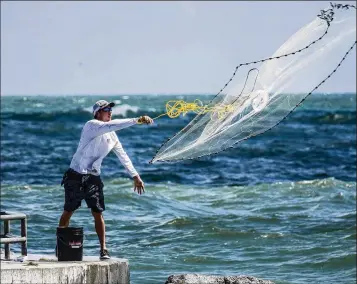  ?? RICHARD GRAULICH / THE PALM BEACH POST ?? Friends Ryun Snyder and Joe Trotta (not pictured), visiting from Fort Myers and trying to get away from the red tide on the west coast of Florida, fish off the Jupiter inlet Monday.