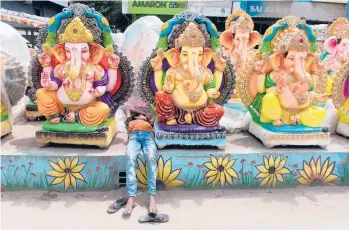  ?? NOAH SEELAM/GETTY-AFP ?? Ganesh Chaturthi festival: A boy rests between idols of the elephant-headed Hindu god Ganesha displayed for sale Thursday at a roadside stall ahead of the Ganesh Chaturthi festival in Hyderabad.