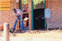  ??  ?? A man clears mud at Snake Ranch Farm’s produce store in San Antonio.