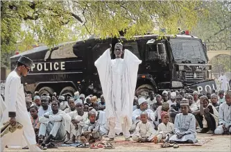  ?? BEN CURTIS THE ASSOCIATED PRESS ?? Muslims make traditiona­l Friday prayers in front of a police riot truck, providing security due to the ongoing general threat of attacks by Islamic extremist group Boko Haram, at a mosque in Kano, northern Nigeria.