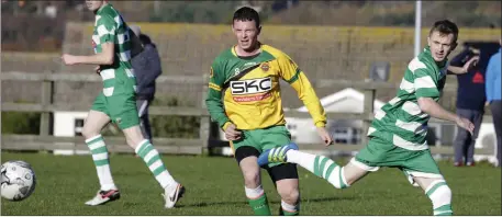  ??  ?? Kyle Devlin of Rathnew and Arklow Celtic’s Paddy Walker keep their eyes on the ball.