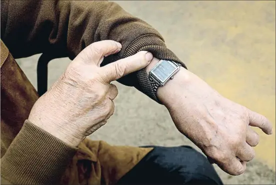  ?? XAVIER CERVERA ?? El hombre de 90 años mira la hora en su reloj en una cuenta atrás hacia la administra­ción de la vacuna, que empieza el domingo en residencia­s