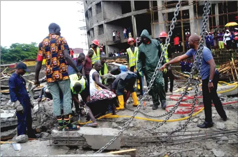  ??  ?? Volunteers and rescue personnel search for people trapped under the rubble at the scene of a collapsed building in Abuja. — AFP photo