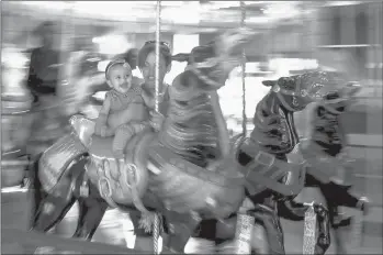  ?? KASSI JACKSON/HARTFORD COURANT PHOTOS ?? Dany Pichardo holds her 8-month-old daughter, Isabella Moran, as she laughs on a carousel ride at the Bushnell Park Carousel 105th birthday party.