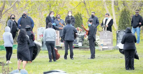  ??  ?? Family members and friends gather for the burial of Jose Agustin Iraheta, who died from COVID-19 in Malden, Massachuse­tts.