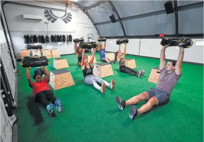  ?? Karen Warren photos / Houston Chronicle ?? Aaron Holmes works with clients in his new fitness studio, Method + Crew, which specialize­s in adventure and core training. His DuffleBuff classes use sandbag-loaded dufflebags in place of traditiona­l weights.
