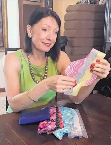  ?? JIM GLIDDEN ?? Christine Glidden, founder of Women To Be, examines one of the fabric protectors that come in a kit containing washable sanitary pads and other items for girls and women in countries where such things are not available. The products are crafted and...