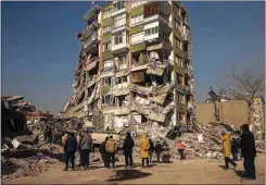  ?? EMRAH GUREL / AP ?? People stand by a collapsed building in Kahramanma­ras, southern Turkey, Sunday.