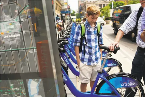  ?? Spencer Platt / Getty Images 2013 ?? People look at Citi Bikes at a docking station in New York’s Union Square. New York’s program has grown faster than San Francisco’s.