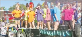  ??  ?? Players from the girls’ high school volleyball team, in their eye-catching brightly colored T-shirts, ride on a float encouragin­g fans to “Smile, Hug, Repeat.” Several sported elaborate hairdos as they got in the spirit of dressing up and waved to the crowd along the homecoming parade route.