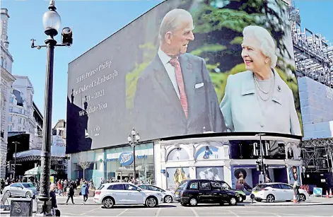  ?? — AFP photos ?? Images of Queen Elizabeth II and Prince Philip are displayed on large screens at Piccadilly Circus in central London, as the funeral for Prince Philip was held in Windsor on April 17.
