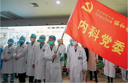  ?? AP ?? Medical workers in Wuhan participat­e in a ceremony to form an ‘‘assault team’’ to battle against a coronaviru­s epidemic.