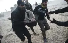  ?? BULENT KILIC/AFP/GETTY IMAGES ?? Iraqi Counter Terrorism Section members carry an injured comrade during clashes with Daesh jihadists near the village of Bazwaya on Monday.