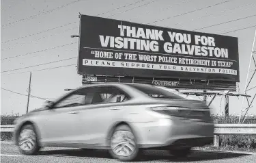  ?? Stuart Villanueva / Associated Press ?? A motorist drives past a billboard critical of Galveston’s police pension plan on the I-45 frontage road near Galveston. The city and the police union reached a tentative agreement on a pension plan on Thursday.