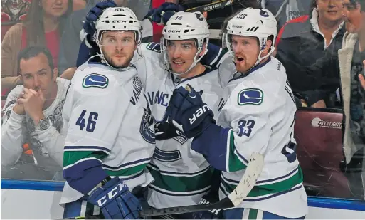  ?? JOEL AUERBACH/ GETTY IMAGES ?? The Canucks’ Alex Burrows, centre, is congratula­ted by Nicklas Jensen, left, and Henrik Sedin after scoring a third- period power- play goal against the Florida Panthers on Sunday in Sunrise, Fla. Jensen, a call- up from the AHL’s Utica Comets, would...