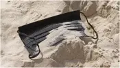  ?? (AFP) ?? A discarded face mask at a beach in Tel Aviv on Sunday