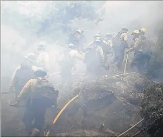  ?? JAE C. HONG/ASSOCIATED PRESS ?? Members of a fire crew walk through thick smoke from the Caldor Fire in South Lake Tahoe, California, on Friday. Fire crews took advantage of decreasing winds to battle the wildfire near popular Lake Tahoe and were even able to allow some people back to their homes.