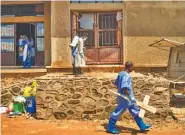  ?? AP PHOTO/JEROME DELAY ?? A morgue employee walks with a cross past others disinfecti­ng the entrance to the morgue in Beni, Congo DRC on Sunday.