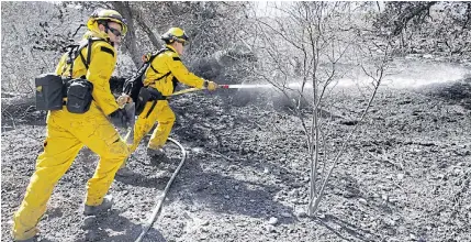  ?? AP ?? Firefighte­rs hose down a hot spot from a wildfire on Saturday in Porter Ranch, California.