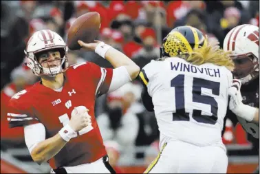  ?? Morry Gash The Assciated Press ?? Wisconsin quarterbac­k Alex Hornibrook readies to pass as Michigan defensive end Chase Winovich tries to break through for the sack during Saturday’s Big Ten game in Madison, Wis. The fifth-ranked Badgers won 24-10.