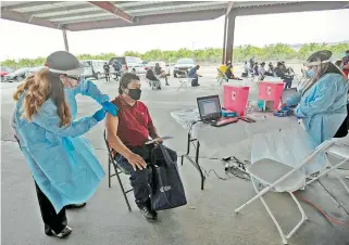  ?? REUTERS ?? Profesiona­les de la salud vacunan a trabajador­es agrícolas en La Meca, California, tras los brotes de Covid19 en la comunidad/