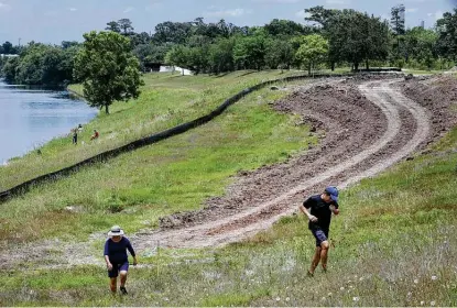  ?? Jon Shapley / Staff photograph­er ?? Juan Aparicio, right, and his wife, Frine, jog along Sims Bayou on Friday near Glenbrook Park. Officials broke ground on a 1.1-mile segment of a hike-and-bike trail connecting the park to a trail east of I-45 along the Houston Botanic Garden site.