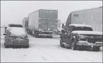  ?? Associated Press ?? Snow covers northbound I-15 in the Cajon Pass between the San Bernardino Mountains and the San Gabriel Mountains in Southern California on Thursday. A powerful winter storm brought a deluge of rain and snow to the region, triggering tornado warnings and bringing post-Christmas travel to a halt on major routes.
