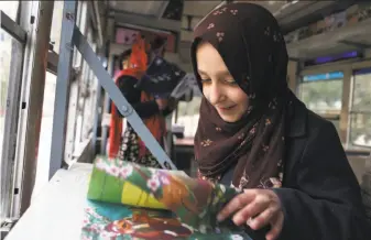  ?? Rahmat Gul / Associated Press ?? Marwa, 11, leafs through a book inside the Charmaghz, a bus converted into a library-on-wheels that makes stops in neighborho­ods throughout the Afghan capital of Kabul.
