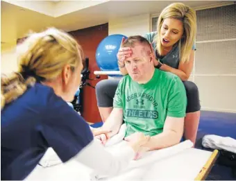  ?? ASSOCIATED PRESS FILE PHOTO ?? Danielle McNicolli, fiancée of Cpl. Nick Tullier, holds his head during a physical therapy session on July 6. Tullier was shot three times by a gunman in Baton Rouge, La., in July 2016.