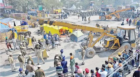  ?? — AFP photo ?? Farmers (right) watch as police (centre) set up road blocks at the Delhi-Haryana state border in Singhu as farmers continue to demonstrat­e against the central government’s recent agricultur­al reforms.