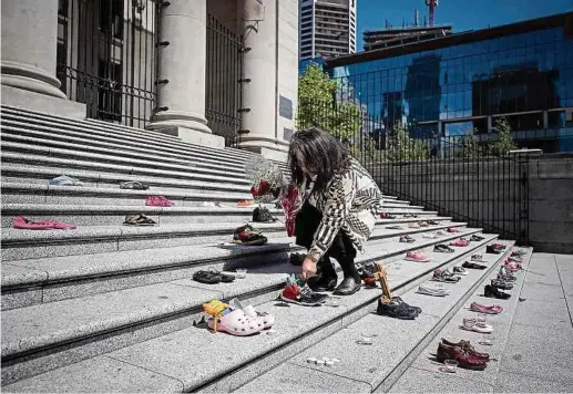  ?? Fotos: dpa ?? Delhia Nahanee legt eine Rose auf eines von 215 Paar Kinderschu­hen auf den Stufen der Vancouver Art Gallery. Das Mahnmal erinnert an die Söhne und Töchter kanadische­r Ureinwohne­r, die in der Residentia­l School nahe der Stadt Kamloops in der Provinz British Columbia zu Tode kamen.