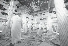  ?? AFP/Getty Images ?? Saudi men look at the debris following a blast inside a mosque in the mainly Shiite Saudi Gulf coastal town of Qatif on Friday. A suicide bomber targeted the mosque after prayers.