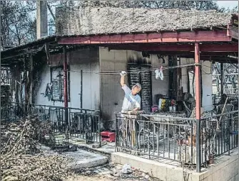  ?? ANGELOS TZORTZINIS / AFP ?? Afortunado. Este hombre inspeccion­a su casa medio destruida por el fuego en Neos Voutzas, cerca de Atenas. La mayoría de sus vecinos no tuvieron tanta suerte y perdieron sus propiedade­s