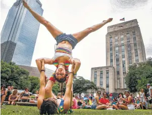  ??  ?? KnottyAcro­Cats performer Sarah Elaine does a split as her partner, Ruthie Ocean, holds her upsidedown during the Houston Pride Festival Saturday in front of City Hall.