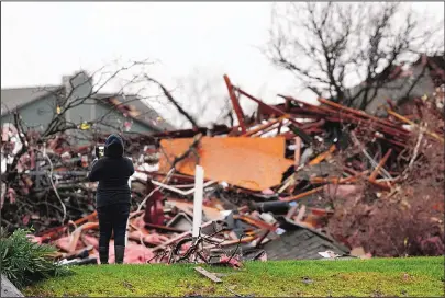  ?? NATHAN HUNSINGER/THE DALLAS MORNING NEWS/AP ?? A resident takes a picture on Sunday near a pile of debris at an apartment complex damaged by Saturday night’s tornado in Garland, Texas. Tornadoes that swept through the Dallas area killed at least 11 people and caused substantia­l damage.