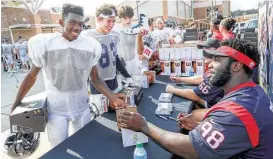  ?? Jon Shapley / Houston Chronicle ?? D.J. Reader (98) and other Texans pass out equipment to Kingwood players, including Darrell Edwards, left, on Tuesday after the team suffered heavy losses during Hurricane Harvey. For a video from the event, go to chron.com/texans.