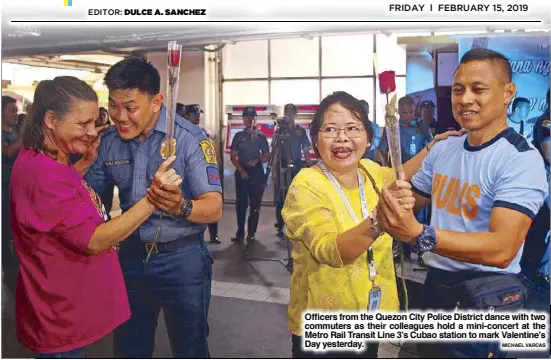  ?? MICHAEL VARCAS ?? Officers from the Quezon City Police District dance with two commuters as their colleagues hold a mini-concert at the Metro Rail Transit Line 3’s Cubao station to mark Valentine’s Day yesterday.