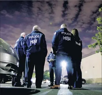  ?? Chris Carlson Associated Press ?? PERSONNEL with Homeland Security Investigat­ions, part of the Department of Homeland Security, talk Jan. 10 before serving an employment audit notice at an L.A. 7-Eleven. Audits were carried out nationwide.