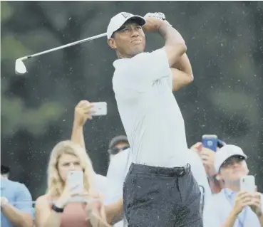  ??  ?? Tiger Woods plays a shot as fans look on during a practice round at Bellerive in St Louis.