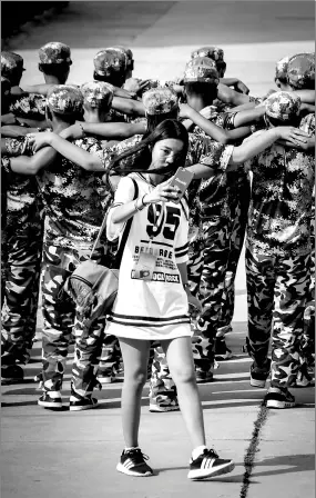  ?? SUN WENTAN / FOR CHINA DAILY ?? A woman takes selfies as students undergo military training in the background in Yantai, Shandong province.