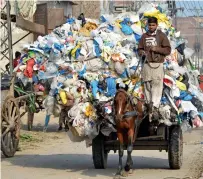  ?? — AFP ?? A boy carries plastic bags on a horse-driven cart in Lahore.