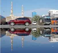  ??  ?? A street scene is reflected in a rain water pond that formed in a parking lot in Al Mahatta area, Sharjah, after the rains on Monday.