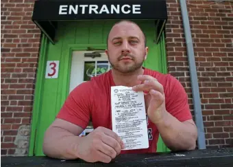  ?? MATT STONE PHOTOS / HERALD STAFF ?? ‘ENOUGH IS ENOUGH’: Dave Blondin, owner of Prime Fitness & Nutrition in Oxford, holds a citation for defying Gov. Charlie Baker’s ban amid the coronaviru­s pandemic.