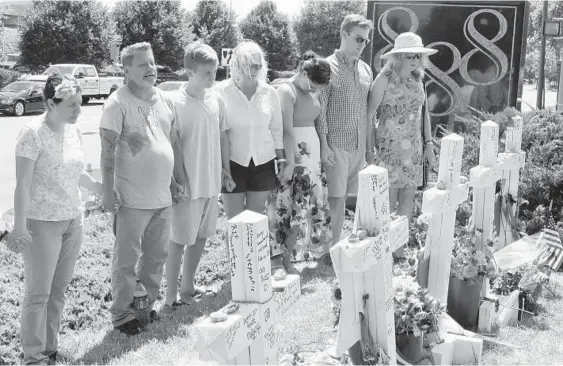  ?? BRIAN WITTE/ASSOCIATED PRESS ?? People pause for a moment Thursday next to a memorial outside the Capital Gazette offices in Annapolis, where five newspaper workers were shot to death last week. Journalist­s around the country observed a moment of silence in commemorat­ion.