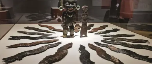  ??  ?? Stunning obsidian eccentrics in the shapes of feathered serpents and lightning bolts surround a female obsidian standing figure on display at the Teotihuaca­n exhibit at the Phoenix Museum of Art.