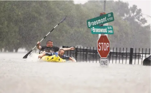  ?? MARK MULLIGAN/HOUSTON CHRONICLE VIA AP ?? Two men in a kayak struggle Sunday against floodwater­s near an overflowin­g Brays Bayou in Houston. The National Weather Service warned that the relentless downpours were expected to continue in Texas and flooding could become much more severe.
