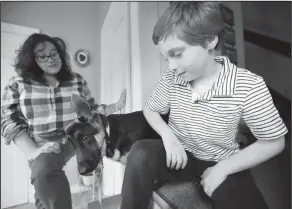  ?? Associated Press ?? Sunscreen: Susan Grenon, left, chats with her son Pauly, right, as their pet German Shepherd "Ginger," center, looks on in an entryway to their home, in Smithfield, R.I. Guenon makes sure her son is lathered with sunscreen before he leaves for school...