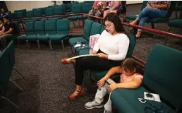  ?? Lezlie Sterling/the Sacramento Bee ?? Prisila Isais takes notes as her daughter Isabel, 8, a Sacramento City Unified School District student, watches a video on her phone while attending a Sacramento ACT town hall meeting about community schools at South Sacramento Christian Center on April 12.