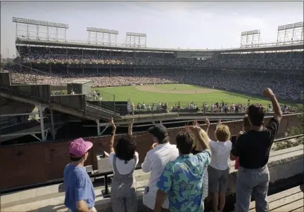  ?? SETH PERLMAN - THE ASSOCIATED PRESS ?? In this July 9, 1990, file photo, spectators watch an All-Star Game practice session from the roof of a building just outside Chicago’s Wrigley Field. This week, Major League Baseball players and owners reached an agreement to play an abbreviate­d, 60-game season that would start July 23 or 24 in teams’ home ballparks. But the seats will be empty. Instead, fans hoping to see a game in person will be have to settle for pressing their faces up against hotel windows, squinting through metal grates or climb to rooftops when baseball returns this month in otherwise empty stadiums.